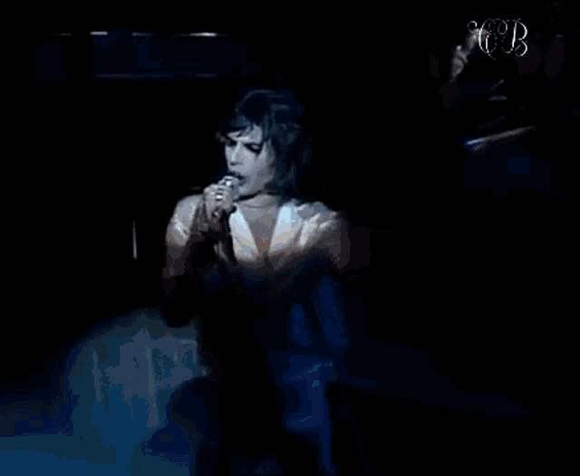 queen freddie mercury is singing into a microphone on stage