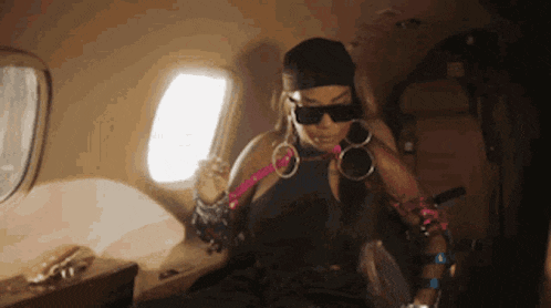 a woman wearing sunglasses and a hat is sitting on an airplane