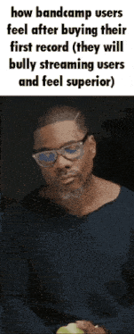 a man wearing glasses and a blue shirt is holding a green apple