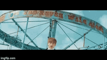 a man is standing in front of a ferris wheel that says ' walk alone ' on it