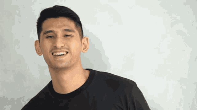 a man wearing a black t-shirt is smiling and looking at the camera
