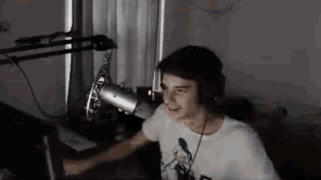 a young boy wearing headphones is sitting in front of a microphone in a dark room .