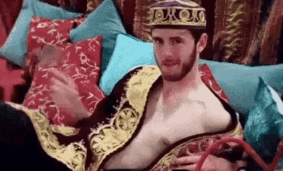 a shirtless man is smoking a hookah while wearing a hat .