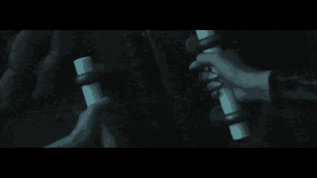 a person holding two sticks in their hands in the dark