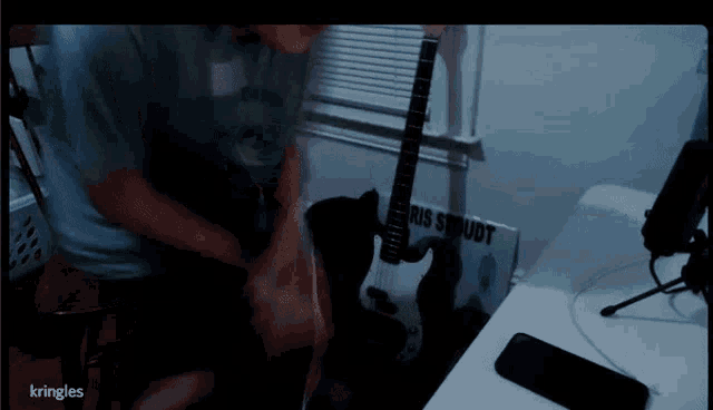 a man is playing a guitar in front of a sign that says kris srudt