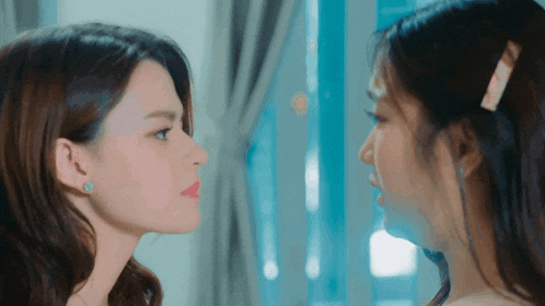 two women are looking at each other with their faces turned towards each other