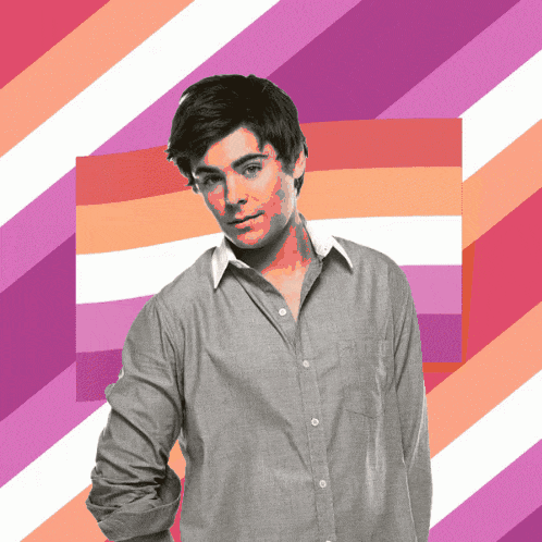 a man in a grey shirt is standing in front of a pink and white striped background