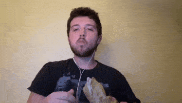 a man with a beard is wearing headphones and holding a bag of food