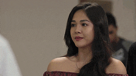 a woman wearing a red off the shoulder top is standing in a room .