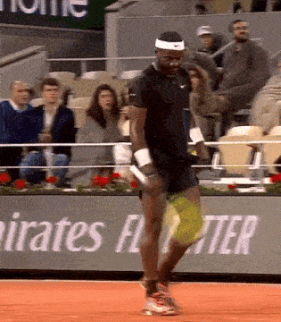 a man is playing tennis in front of a banner that says emirates fly better