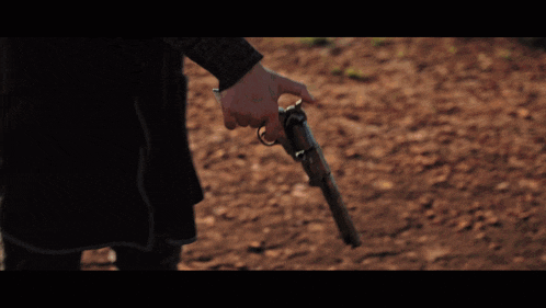 a person holding a gun in a field of dirt