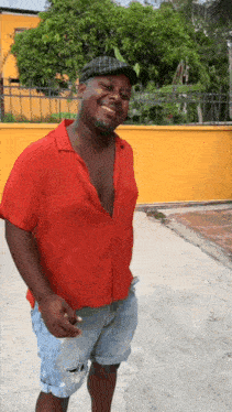 a man in a red shirt and blue shorts is smiling and holding a cigarette