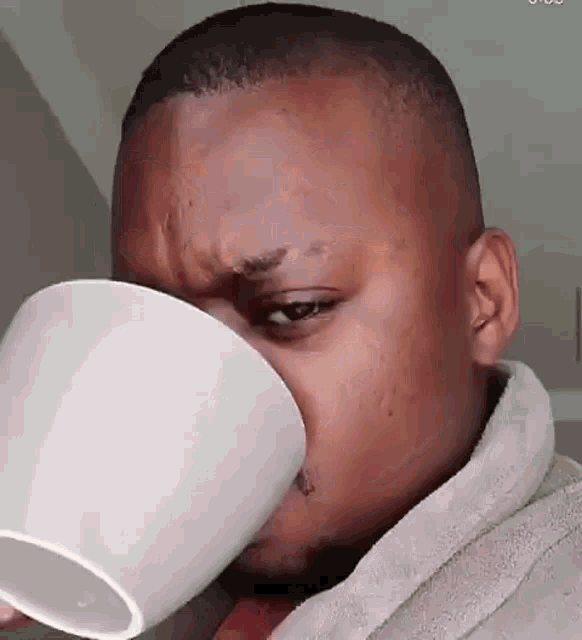 a man is drinking a cup of coffee with his mouth open .