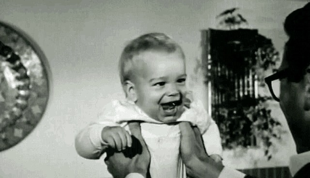 a man is holding a baby in his arms and the baby is laughing