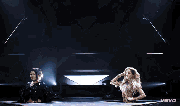 two women are dancing on a stage with the word vevo on the bottom
