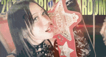 a woman is holding a star shaped item that says stardom on it