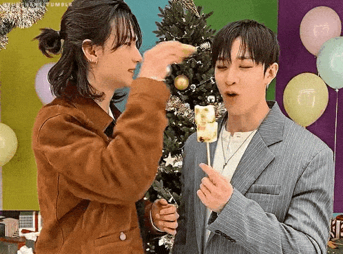 a couple of men are standing next to each other eating marshmallows .