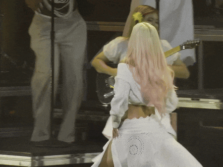 a woman with pink hair is playing a guitar on stage