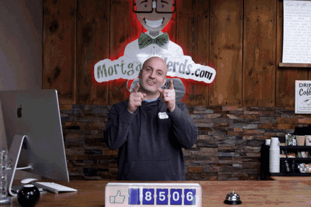 a man giving a thumbs up in front of a mortgagenerds.com sign