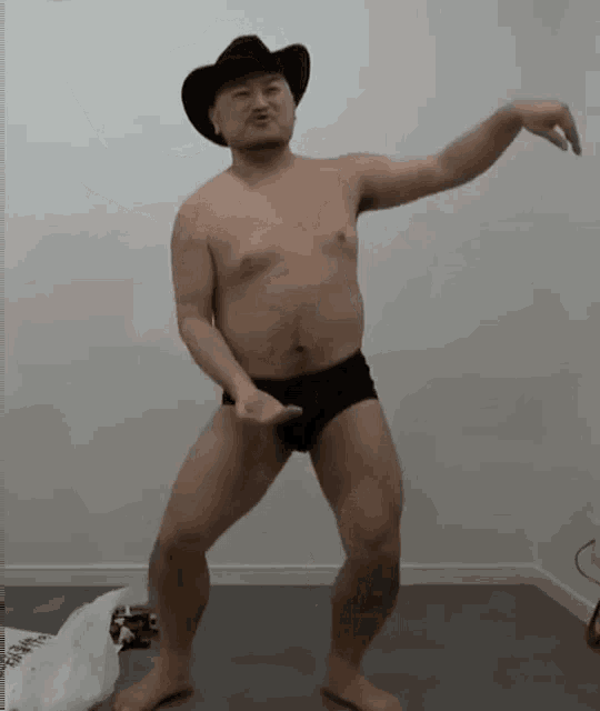 a shirtless man wearing a cowboy hat and underwear is dancing in a room .