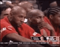 a group of men are sitting in a stadium watching a game of basketball .