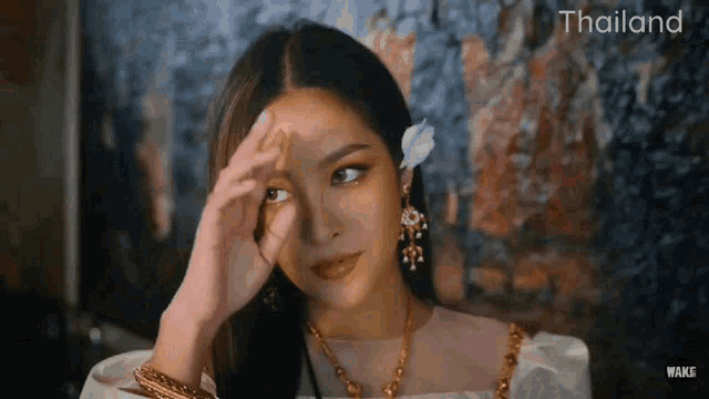 a woman with a flower in her hair is wearing a white dress and earrings .