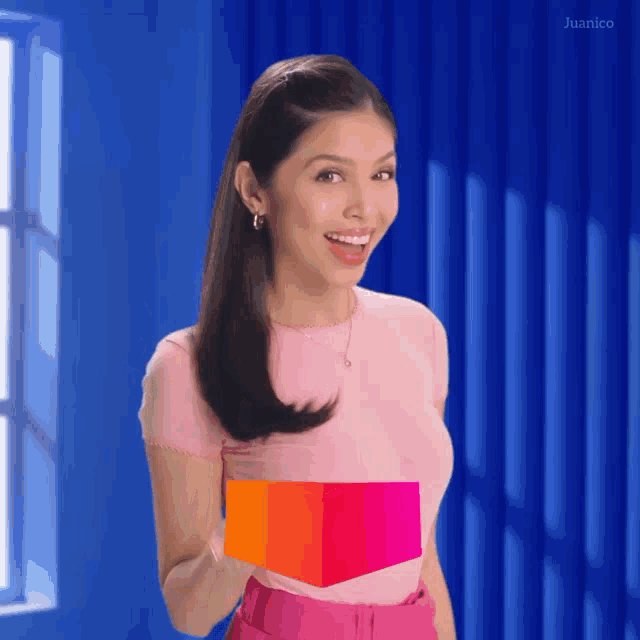 a woman in a pink shirt is holding a cube in her hand
