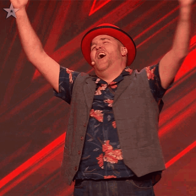a man with his arms in the air wearing a red hat and a floral shirt