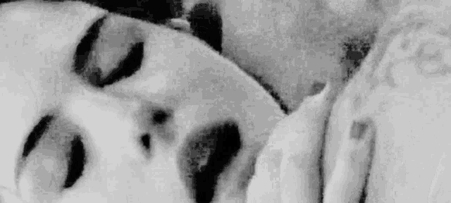 a black and white photo of a man and a woman laying on a bed .