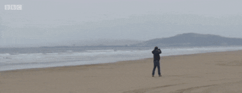 a man standing on a beach with lol written in yellow letters
