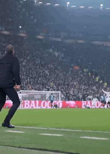 a man runs on a soccer field in front of a sign that says baloco