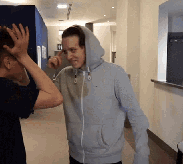a man wearing a grey hoodie with a tommy hilfiger logo on it