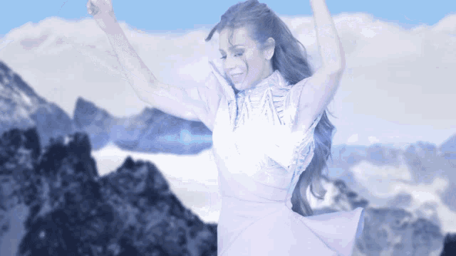 a woman in a purple dress is dancing in front of a snowy mountain