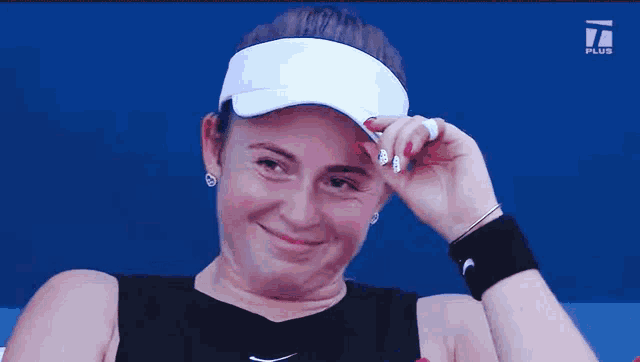 a woman wearing a visor and a wristband with the letter i on it
