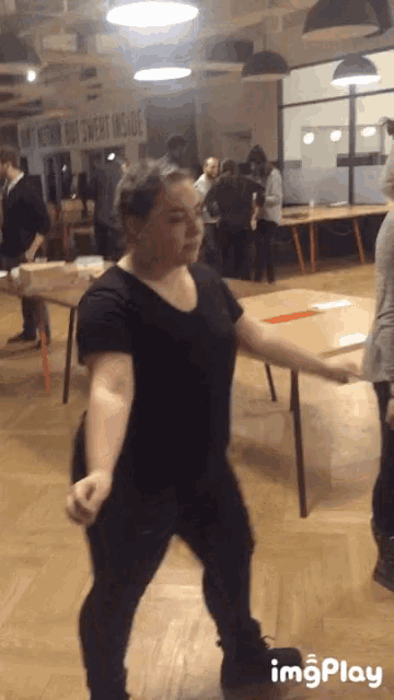 a woman in a black shirt is dancing in a room with a sign on the wall that says insight inside