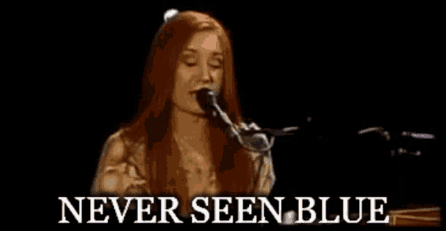 a woman singing into a microphone with the words " never seen blue " below her