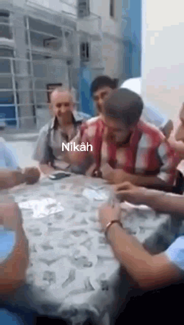 a group of men are sitting around a table with nikah written on the top
