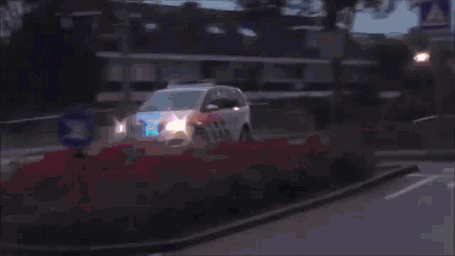 a police car with a blue light on the top is driving down a street