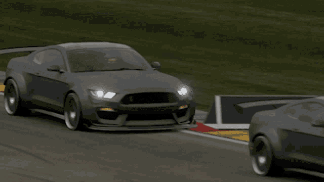 a black car is driving down a race track with a yellow sign that says ' rs ' on it