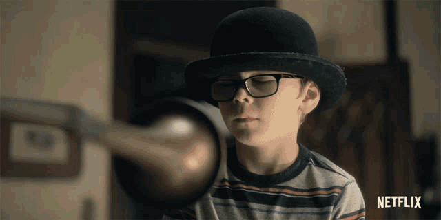 a boy wearing glasses and a bowler hat has a netflix logo in the corner