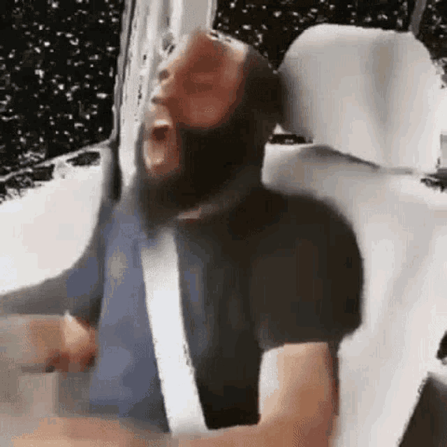 a man with a beard is sitting in the back seat of a car and screaming .