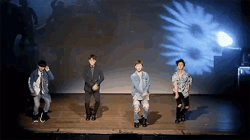 a group of young men are dancing on a stage in front of a flower projection