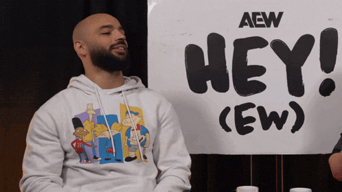 a man sitting in front of a sign that says hey ew