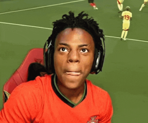 a man wearing headphones and a red nike shirt smiles on a tennis court