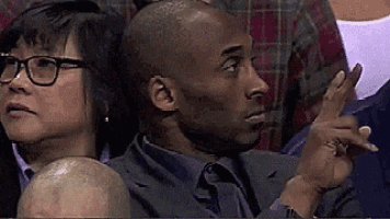 a man in a suit and tie is sitting in a stadium with a woman behind him .