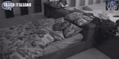 a person is sleeping on a bed with a floral comforter and pillows .