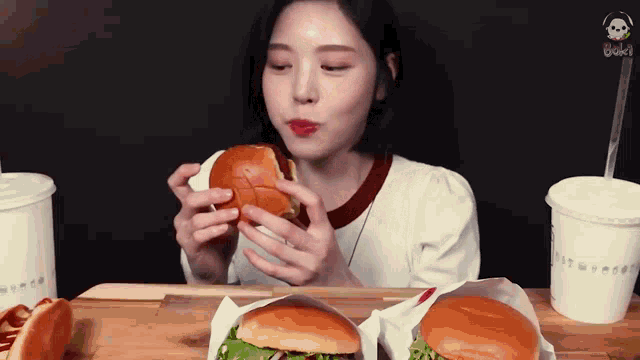 a woman is sitting at a table eating a hamburger and french fries .