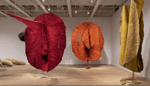 a row of red and yellow sculptures hanging in a room