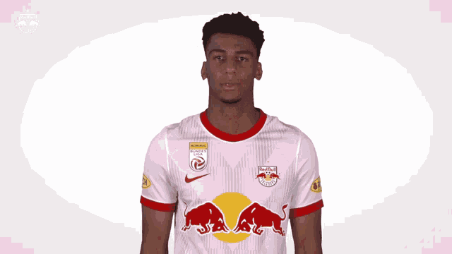 a man wearing a red bull shirt is covering his eyes with his hands