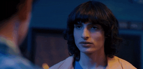 a young man with curly hair is looking at another man .